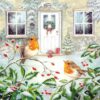 Two robins perched on a snowy branch outside a festive, snow-covered house with Christmas decorations.
